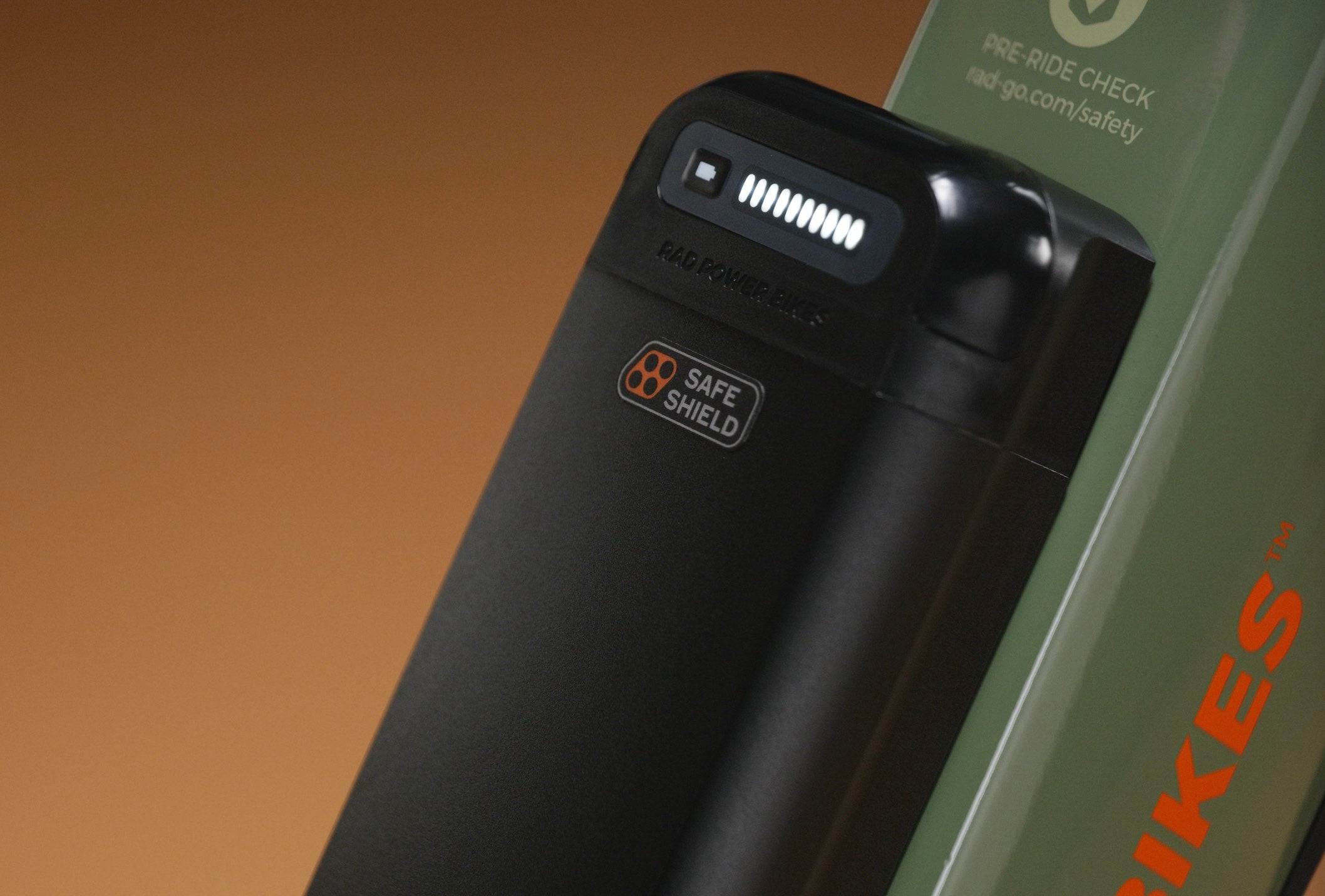 A close-up of a Safe Shield battery on a green electric bike in a studio setting.