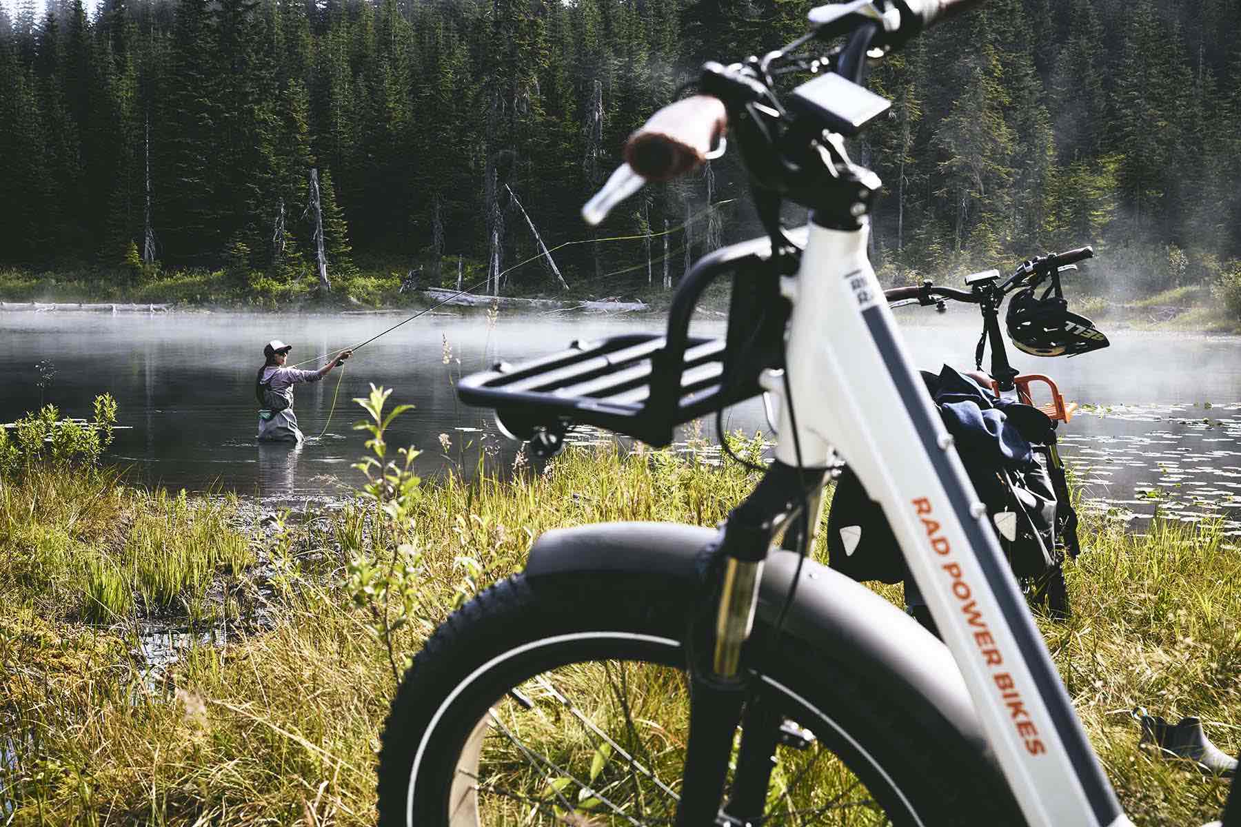 A woman goes fishing alongside a RadMini Step-Thru electric bike.