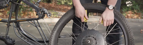 A man replaces his electric bike tire on a rural road.