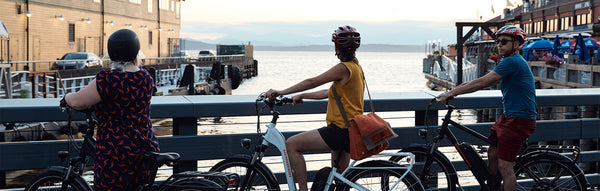 Individuals ride Rad Power Bikes across bridge.