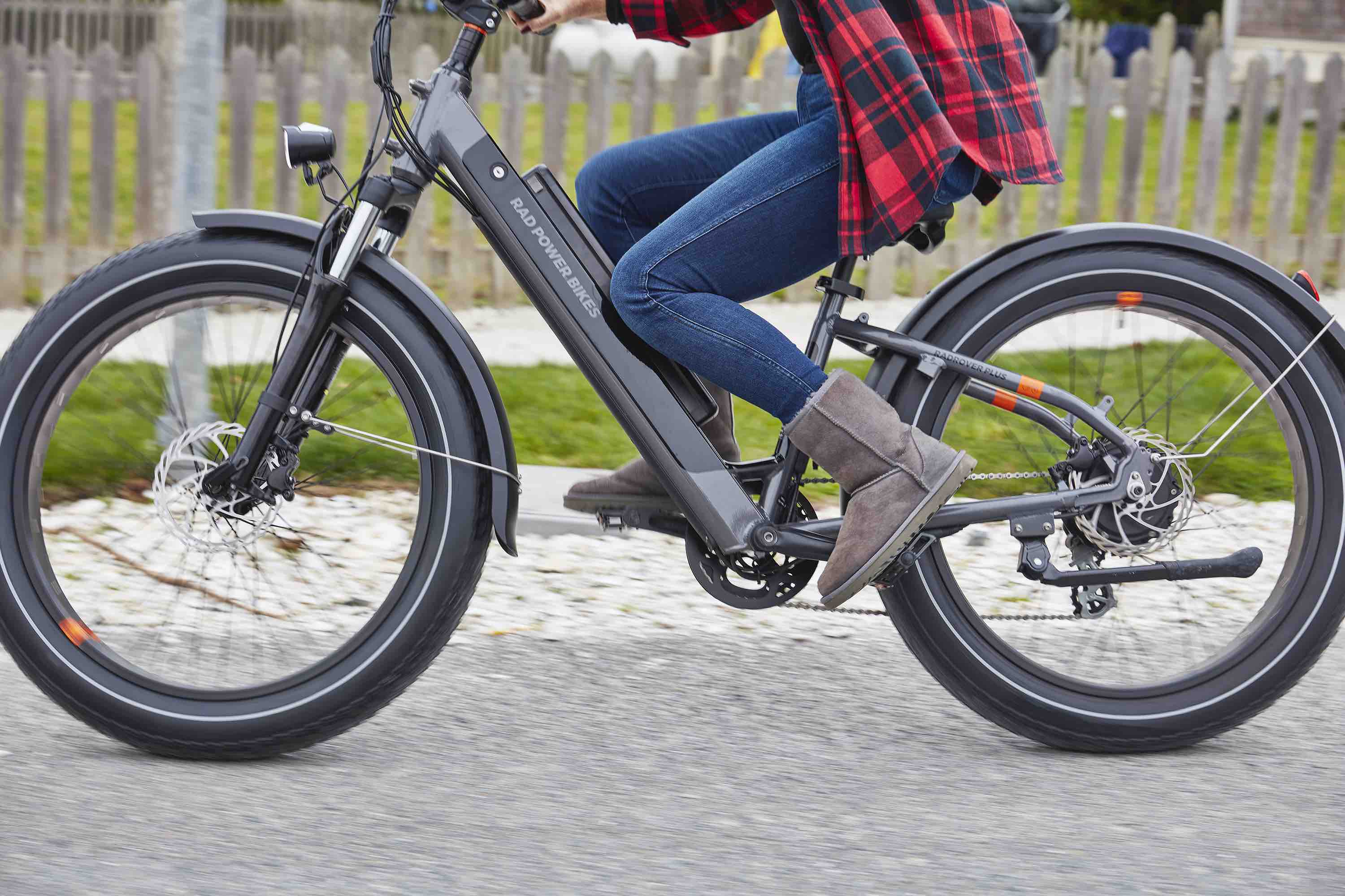 A close-up of the RadRover 6 Plus electric off-road bike riding on a suburban street. The rider wears fall attire.