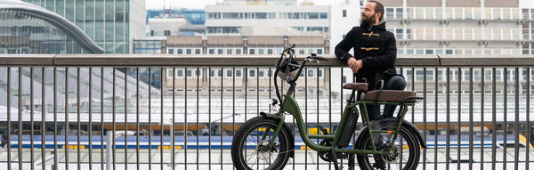 A man in fall attire rides a RadRunner 2 electric utility bike amid a fall backdrop.