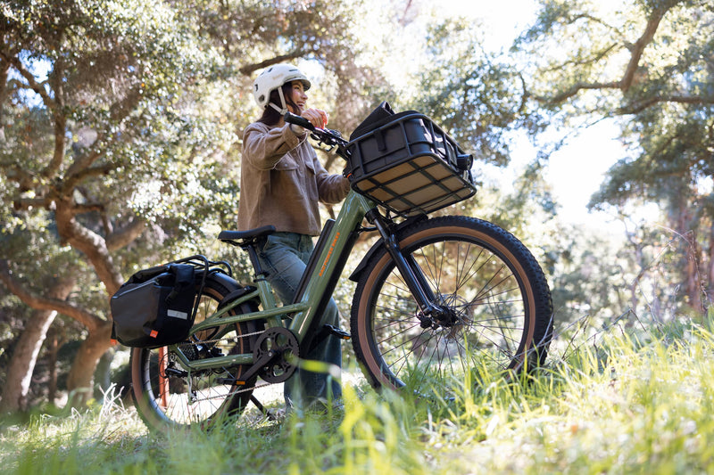 Woman standing next to a Radster Trail electric off-road bike in a grassy area