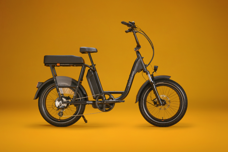 A matte black electric bike with a black passenger package against a gold background. 